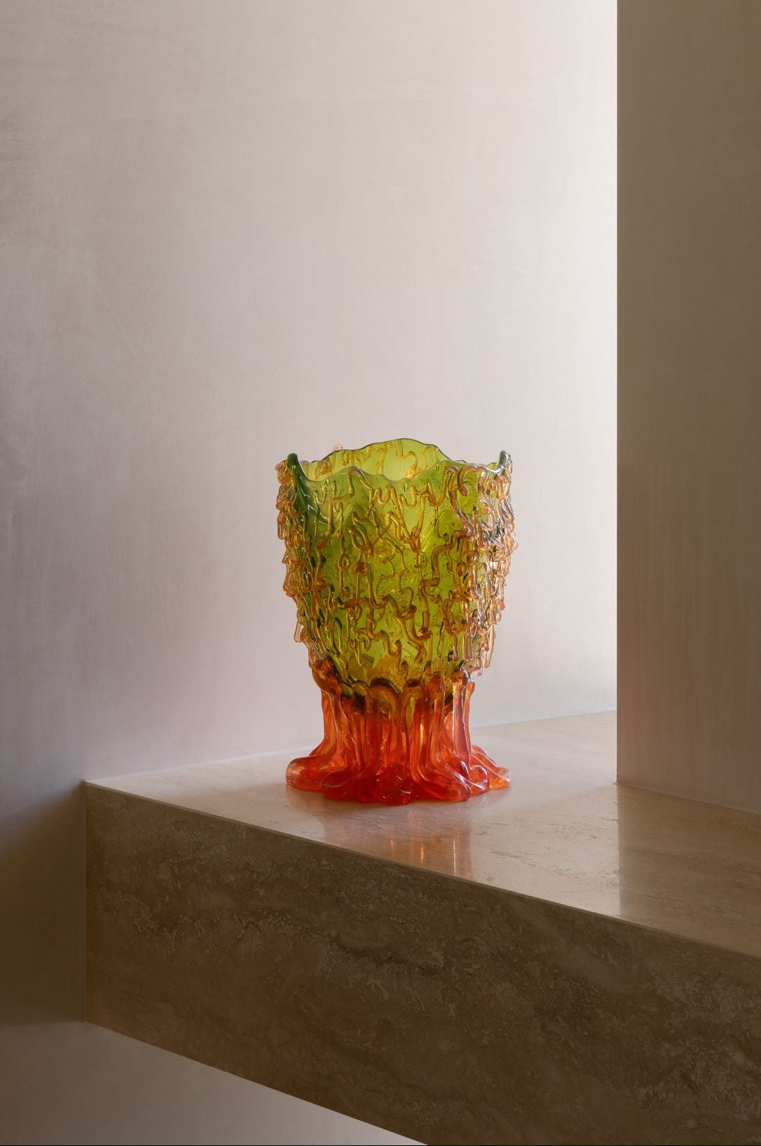 A sculptural vase with a textured, organic pattern in green, and orange.